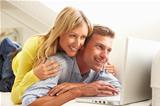 Couple Using Laptop Relaxing Sitting On Sofa At Home