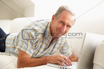 Senior Man Using Laptop Relaxing Sitting On Sofa At Home