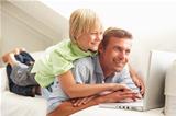 Father And Son Using Laptop Relaxing Sitting On Sofa At Home