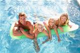 Family Outside Relaxing In Swimming Pool