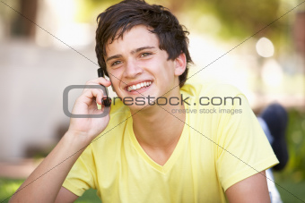 Teenage Boy Laying In Park Using Mobile Phone