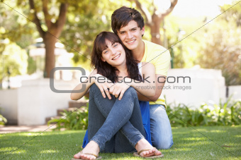 Portrait Of  Romantic Teenage Couple Sitting In Park