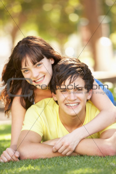 Portrait Of  Romantic Teenage Couple Sitting In Park