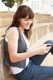 Teenage Student Sitting Outside On College Steps Using Mobile Phone