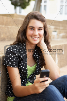 Teenage Student Sitting Outside On College Steps Using Mobile Phone
