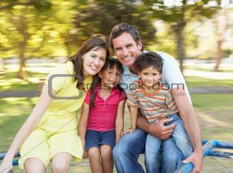 Family Riding On Roundabout In Park