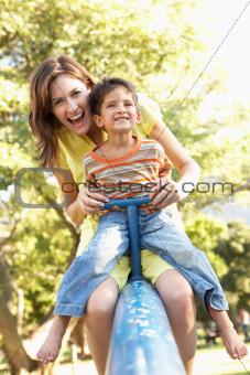 Mother And Son Riding On See Saw In Playground