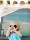 Baby in glasses laying on sun bed