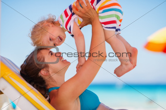 Happy mother playing with baby on sunbed