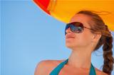 Happy woman in sunglasses on windy beach looking on copy space