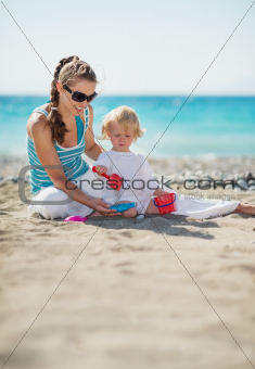 Mother and baby playing with sand on beach