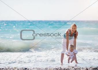Mother and baby playing with sea waves