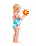 Baby girl in swimsuit holding pinwheel