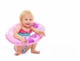 Baby girl in swimsuit sitting with inflatable ring