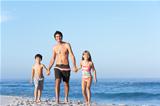 Father Running With Children Along Sandy Beach