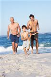 Grandfather, Father and Grandson Running Along Beach