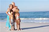 Grandparents And Grandchildren Standing On Sandy Beach