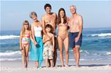 Three Generation Family On Holiday Walking Along Beach