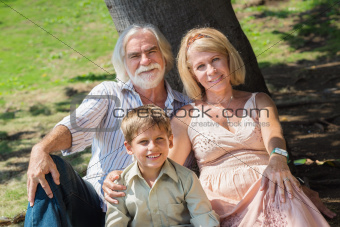 grandparents playing with child under tree in park