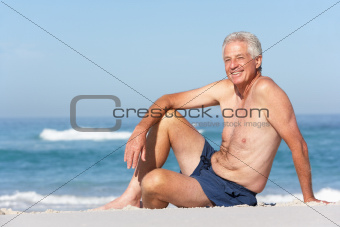 Senior Man On Holiday Sitting On Sandy Beach