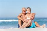 Senior Couple On Holiday Sitting On Sandy Beach