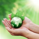 Human hands holding green earth with a leaf