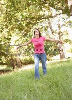 Young Woman Running Through Long Grass In Park