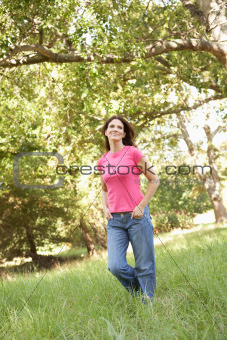 Young Woman Walking Through Long Grass In Park