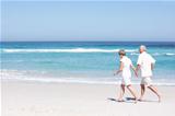 Senior Couple On Holiday Running Along Sandy Beach