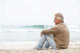 Senior Man On Holiday Sitting On Winter Beach