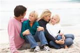 Young Family Sitting On Winter Beach