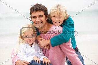 Father And Children Sitting On Winter Beach Together