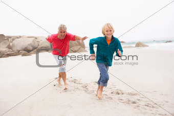 Grandfather Chasing Grandson Along Winter Beach