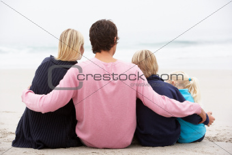 Back View Of Young Family Sitting On Winter Beach