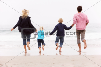 Back View Of Young Family Running Along Winter Beach