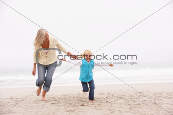 Grandmother And Granddaughter Running Along Winter Beach