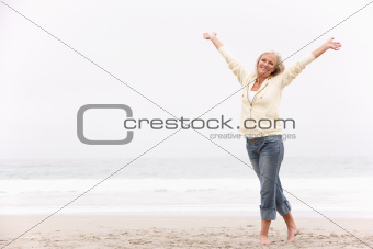 Senior Woman With Arms Outstretched On Winter Beach