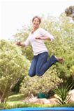 Woman Jumping On Trampoline In Garden