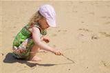 Girl drawing on white beach with stick