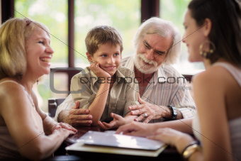 Happy parents and grandparents with boy in bar