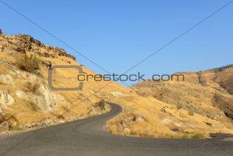 Curved black road in yellow hills