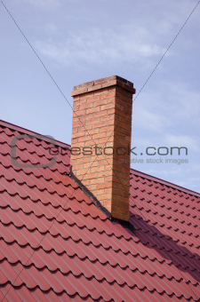 Brown tiled roof yellow brick chimney on sky 