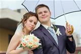 bride and groom under a white umbrella