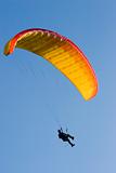 Orange paraglider in a blue sky