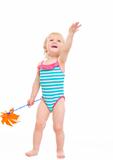 Happy baby in swimsuit with pinwheel pointing up