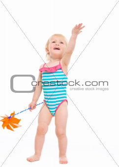 Happy baby in swimsuit with pinwheel pointing up