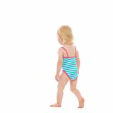 Baby in swimsuit walking away. Rear view