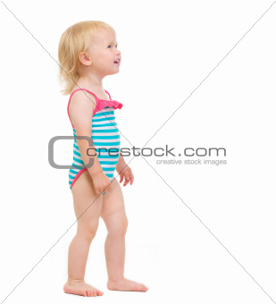 Curious baby in swimsuit looking on copy space