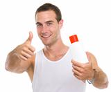 Happy young man showing sun screen creme and thumbs up