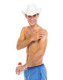 Happy man in hat applying sun block creme on arm